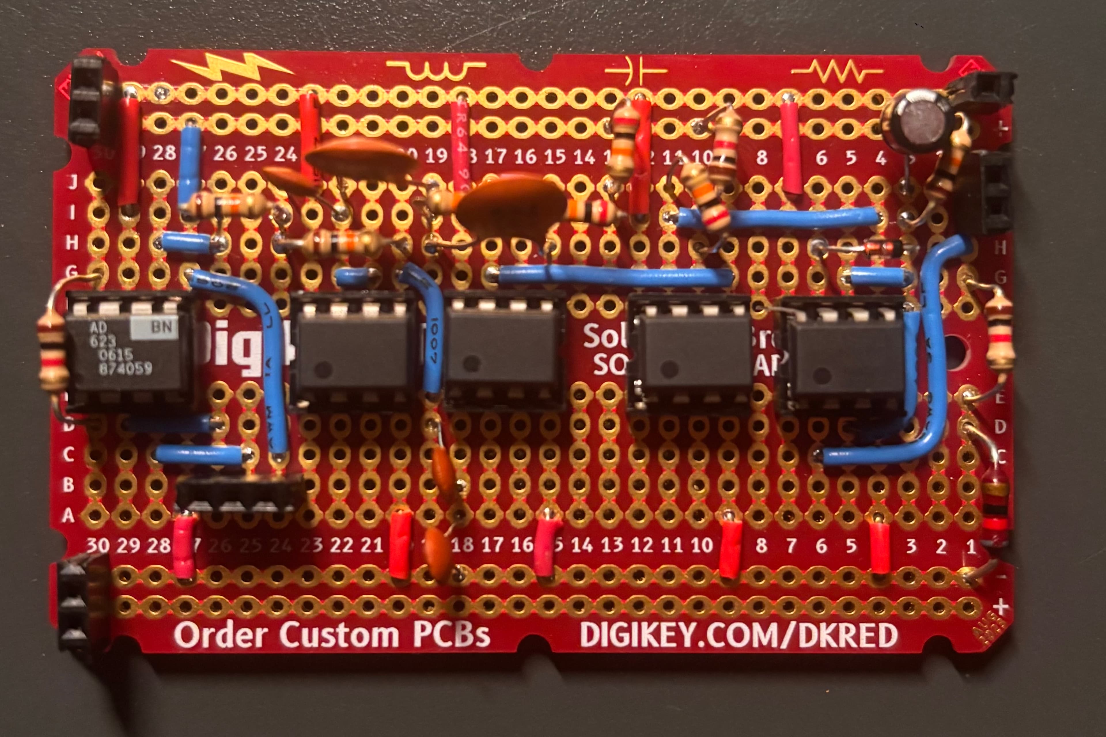 Hand-soldered perfboard — an instrumentation amplifier and four op-amps in a row, with resistors, capacitors, and jumper wires implementing the analog EMG front end